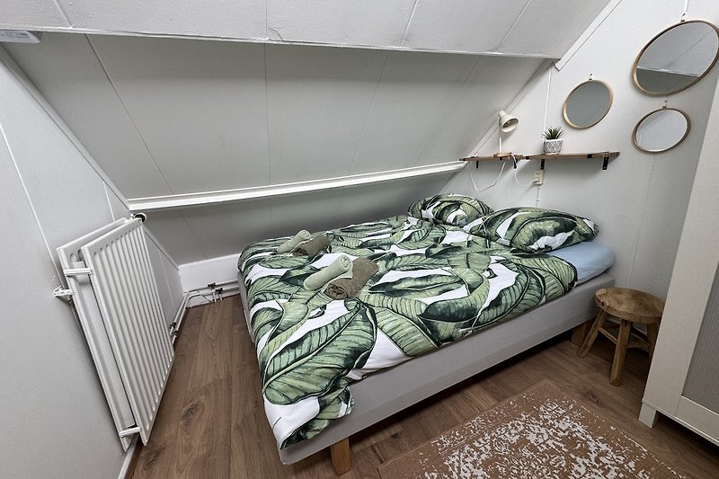 Schlafzimmer mit gemütlichem Bett, Metallrahmen und Holzboden.