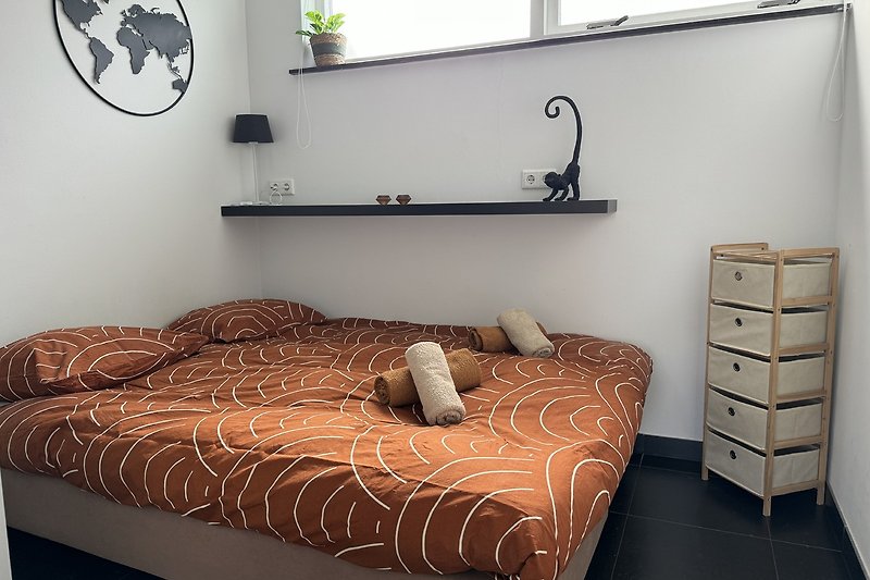 Stilvolles Schlafzimmer mit Holzbett, Pflanzen und großem Fenster.