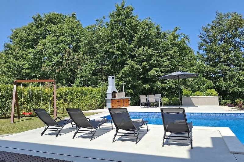 Entspannen Sie am Pool mit Sonnenliegen und schattigem Garten.