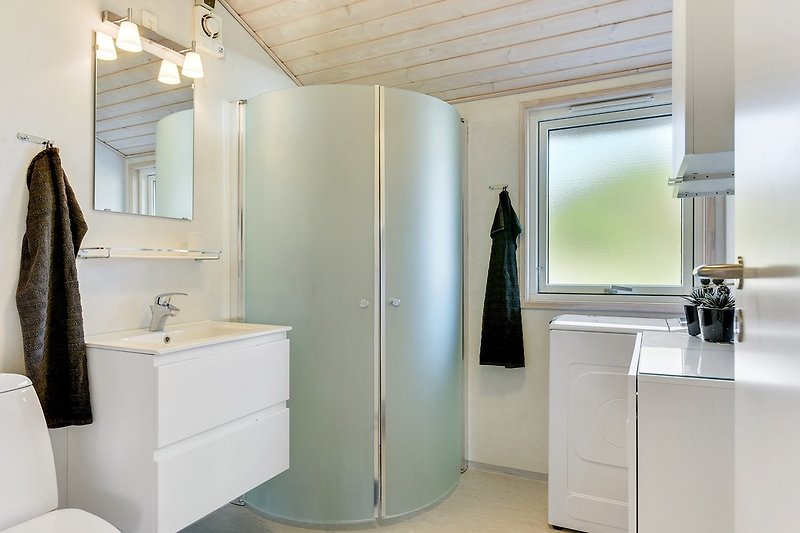 Badezimmer mit Toilette, Waschbecken, Dusche, Waschmaschine und herrlicher Fußbodenheizung.
