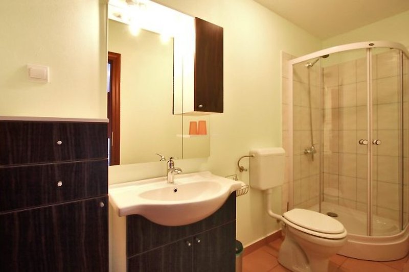 Schönes Badezimmer mit lila Wand, schwarzer Spüle und Holzboden.