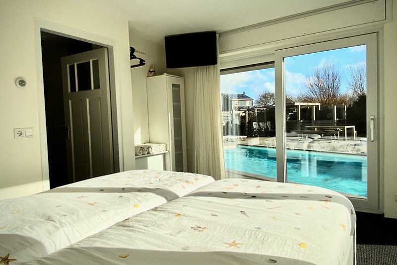 Schlafzimmer mit stilvollem Interieur und Blick auf den Pool.