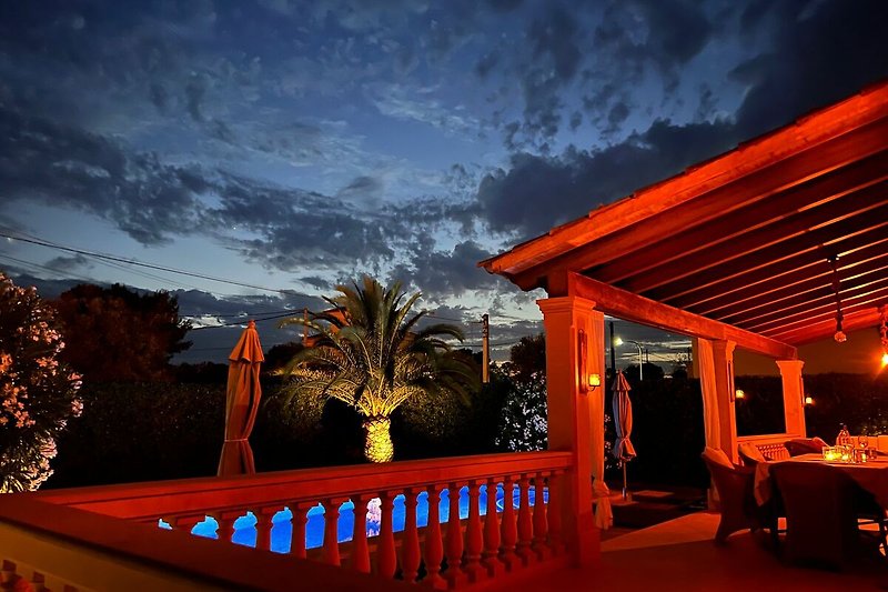 Schönes Ferienhaus mit Pool und tropischem Garten am Abend.