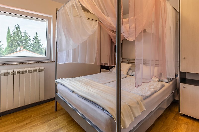 Udobna spavaća soba s drvenim krevetom i prozorom.