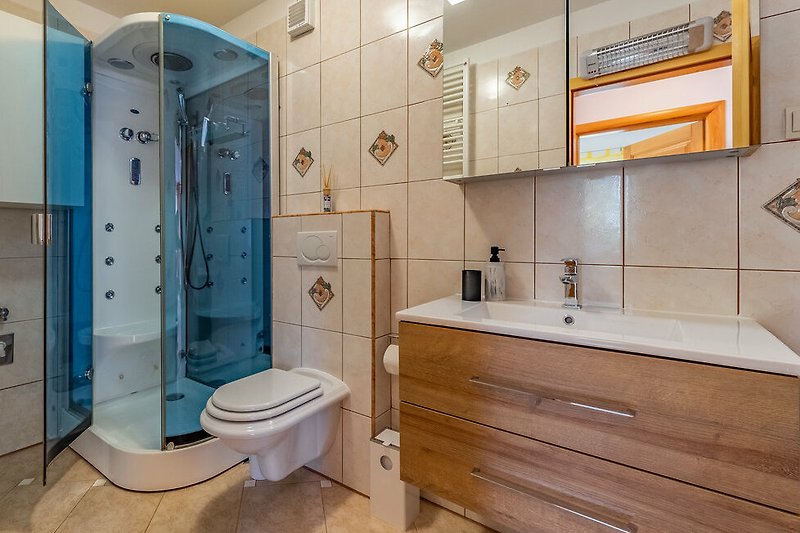 Predivna kupaonica s drvenim ormarićem, ogledalom i ljubičastim detaljima.