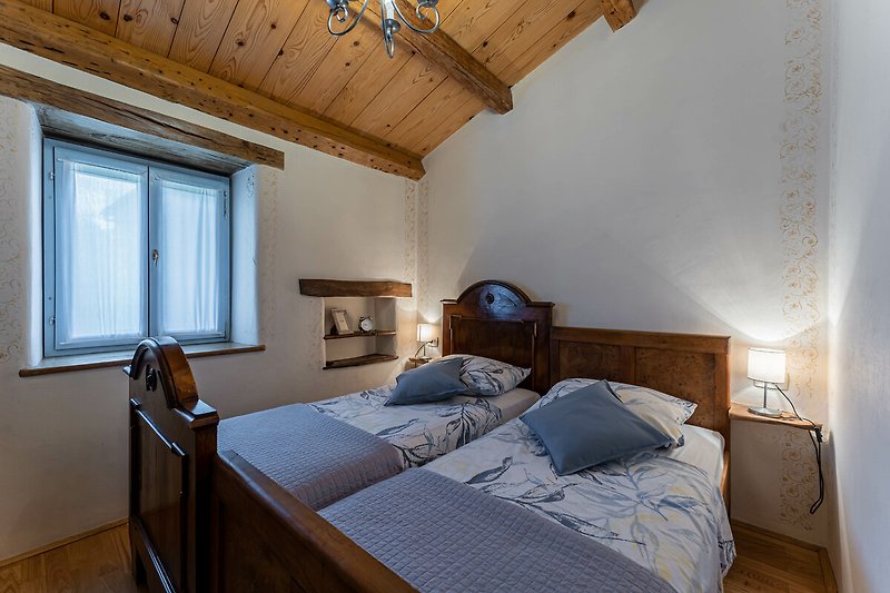 Predivna spavaća soba s udobnim drvenim krevetom i lijepim pogledom kroz prozor.