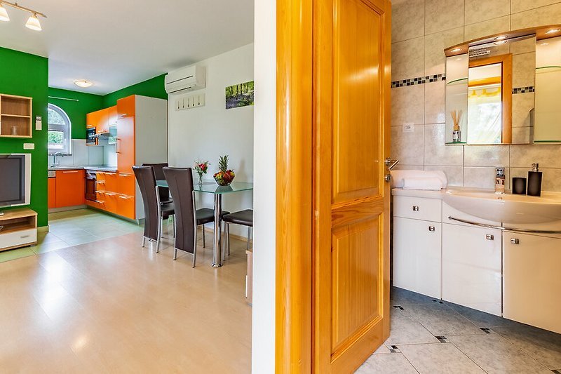 Predivan interijer kuhinje s drvenim kabinetskim elementima i modernim kuhinjskim aparatima.