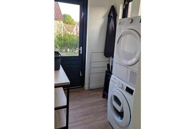 Spacious laundry room with washing machine, dryer and storage for garden furniture and bicycles.