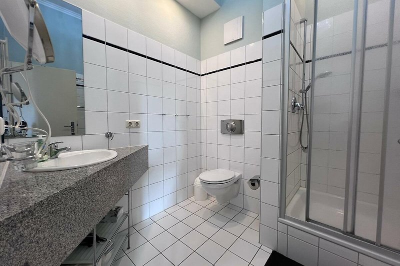 Modernes Badezimmer mit Spiegel, Waschbecken, WC und Dusche.