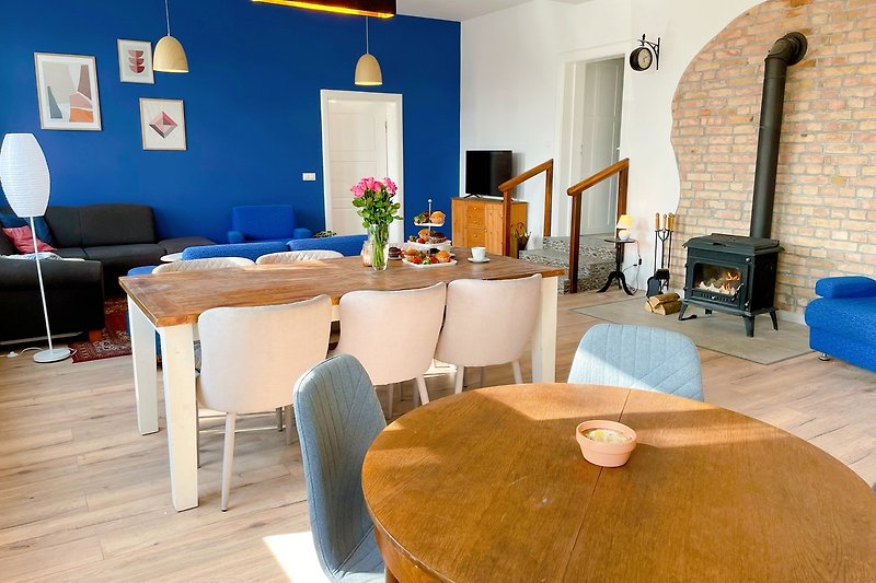 Gemütliches Wohnzimmer mit Holzmöbeln, blauen Akzenten und Pflanzen. Perfekt zum Entspannen und Kaffeetrinken.