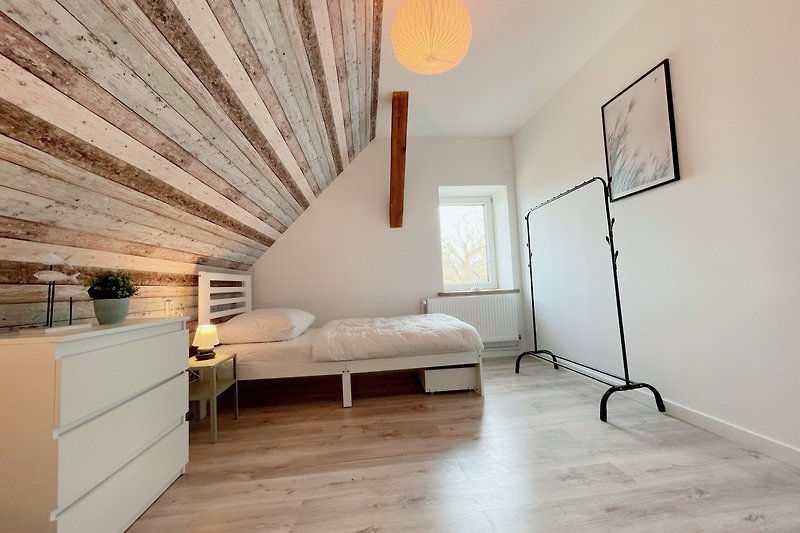 Gemütliches Wohnzimmer mit Holzmöbeln und bequemem Bett. Perfekt zum Entspannen und Schlafen.