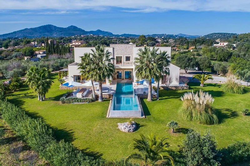 Villa mit Pool, Palmen und gepflegter Landschaft.
