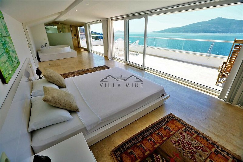 Luxuriöses Schlafzimmer mit Meerblick und Boot vor dem Fenster.