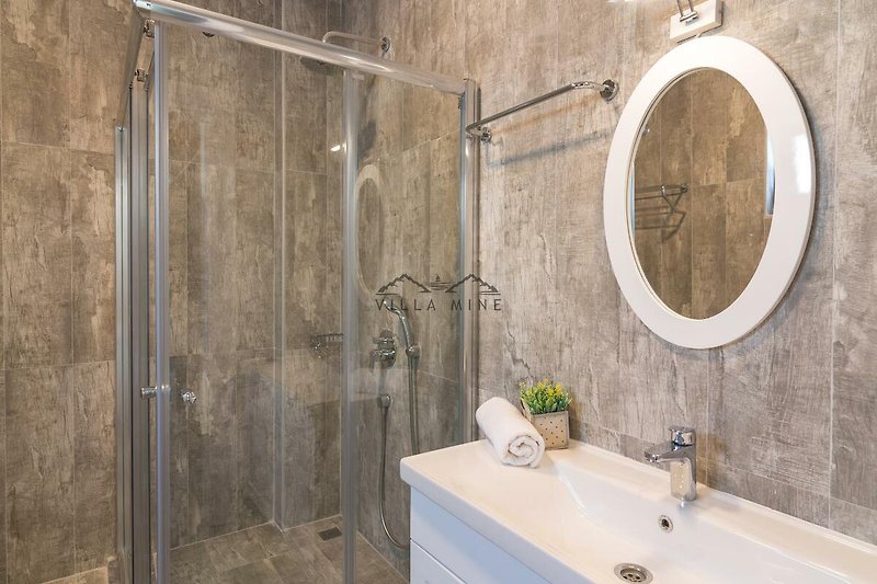 Badezimmer mit Spiegel, Waschbecken, Pflanze und Dusche - modern und stilvoll!
