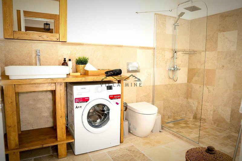Modernes Badezimmer mit Dusche, Waschmaschine und Trockner.