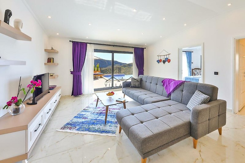 Wohnzimmer mit violettem Sofa, Holztisch und Pflanzen.