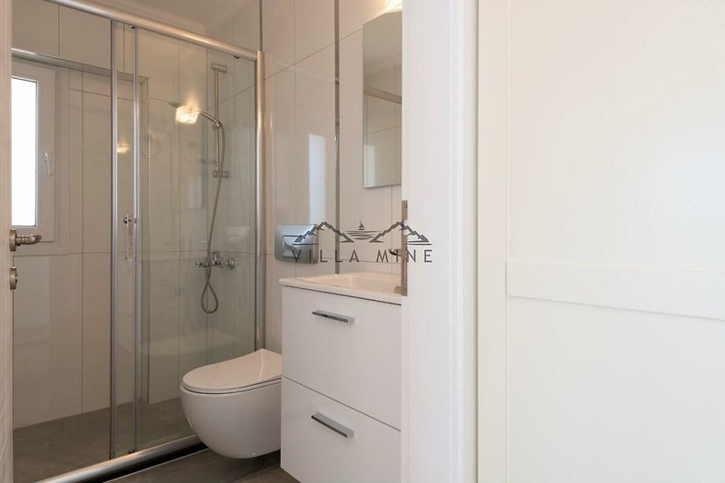 Modernes Badezimmer mit Spiegel, Armatur und Dusche.