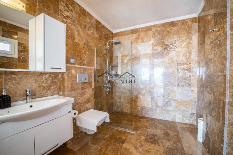 Badezimmer mit Spiegel, Waschbecken, Badewanne und Fliesen.
