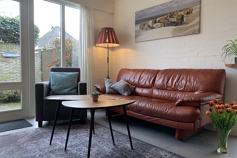 Wohnzimmer mit bequemer Couch, Holzmöbeln, Pflanzen und Lampen. Gemütliche Atmosphäre.