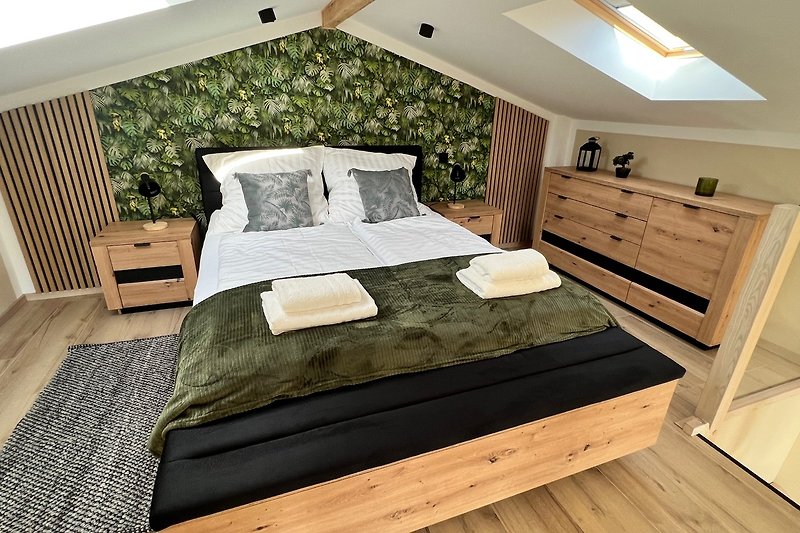 Schlafzimmer mit Holzbett, Nachttisch und Lampe. Natürliche Einrichtung .