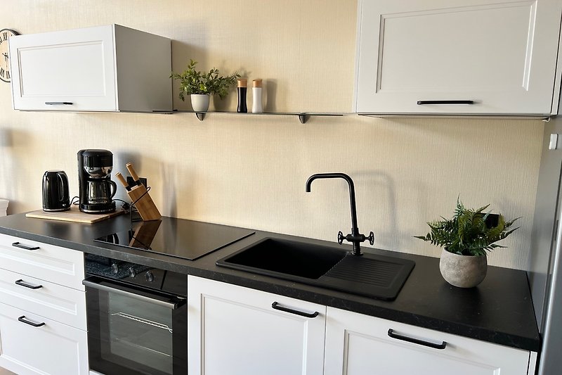 Moderne Küche mit weißen Schränken und Granit-Arbeitsplatte. Hochwertige Ausstattung.
