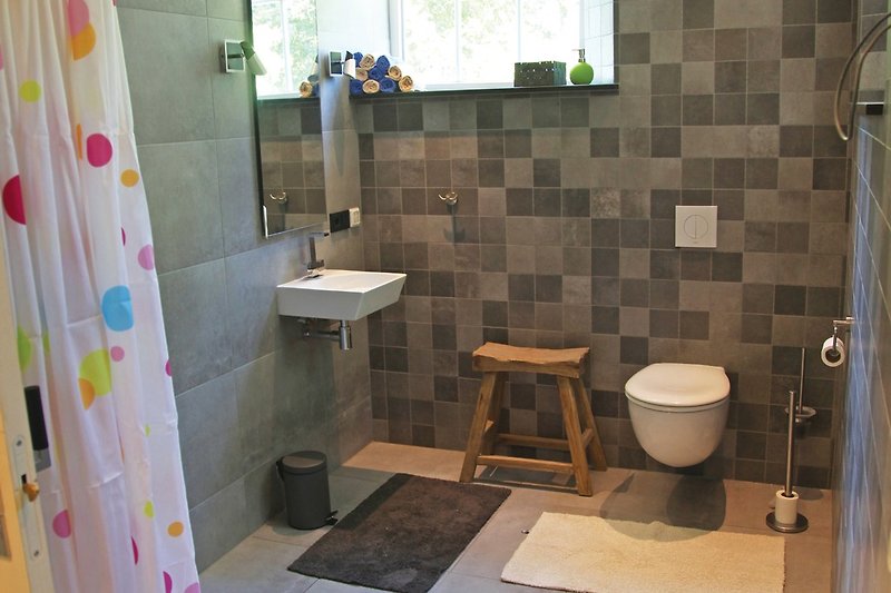 Ferienhaus ievers yn Fryslân hat zwei Badezimmer mit Dusche, Waschbecken und Toilette.