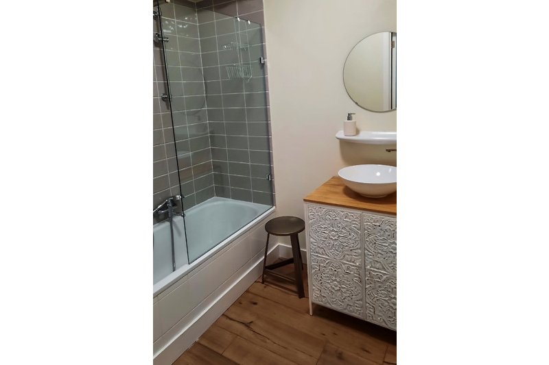Badkamer met wastafel, ligbad en douchescherm