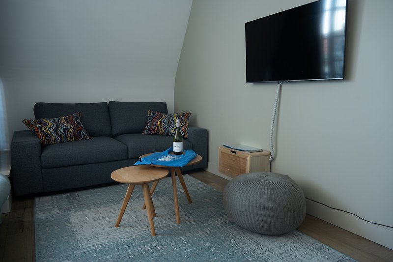 Wohnzimmer mit Fernseher, Couch, Tisch & Holzdetails. Gemütliche Atmosphäre.