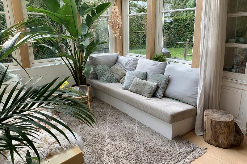 Wohnzimmer mit bequemer Couch, Pflanzen und Fenster.