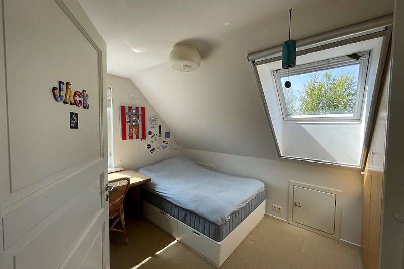 Gemütliches Schlafzimmer mit bequemem Bett und Fenster.