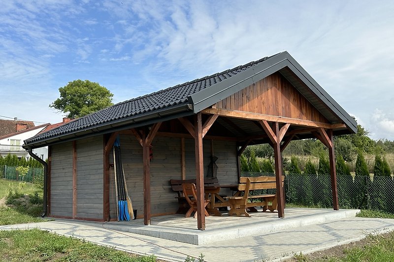 Uroczy domek z ogrodem, drewnianym dachem i meblami ogrodowymi.