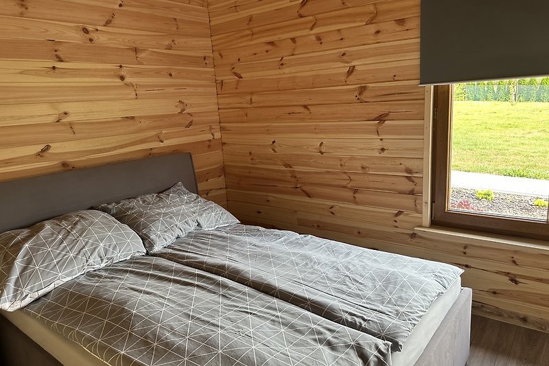 Elegancka sypialnia z drewnianym sufitu i wygodnym łóżkiem.