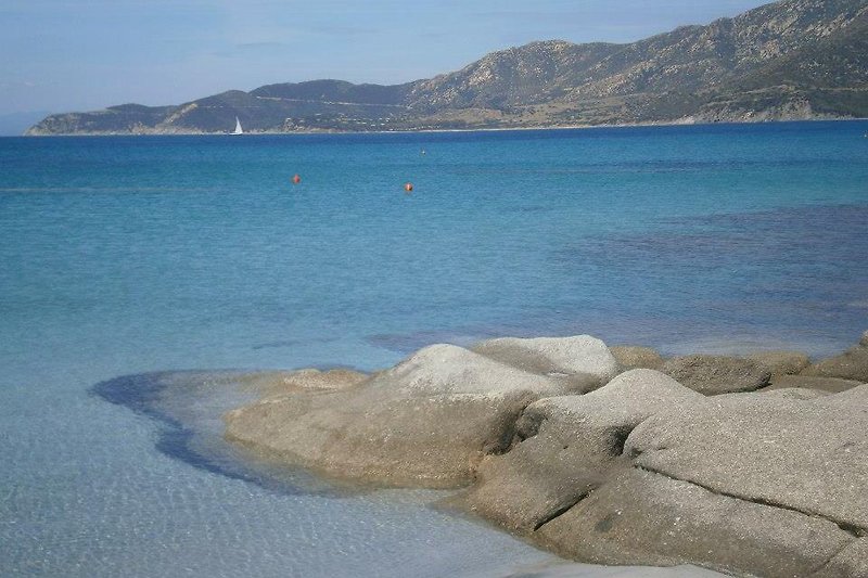 Una vista mozzafiato con un mare azzurro, una spiaggia di sabbia bianca e una costa rocciosa.