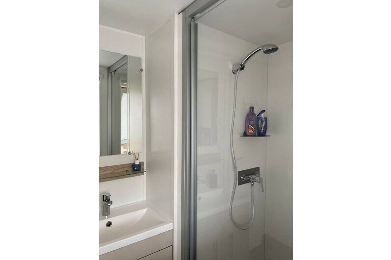 Schönes Badezimmer mit Spiegel, Dusche und Waschbecken.