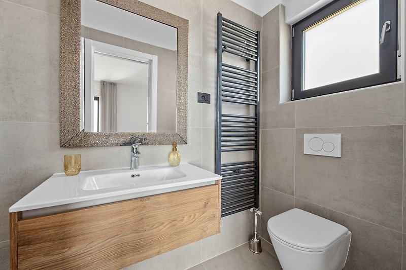 Stilvolles Badezimmer mit Spiegel, Waschbecken und Badewanne.