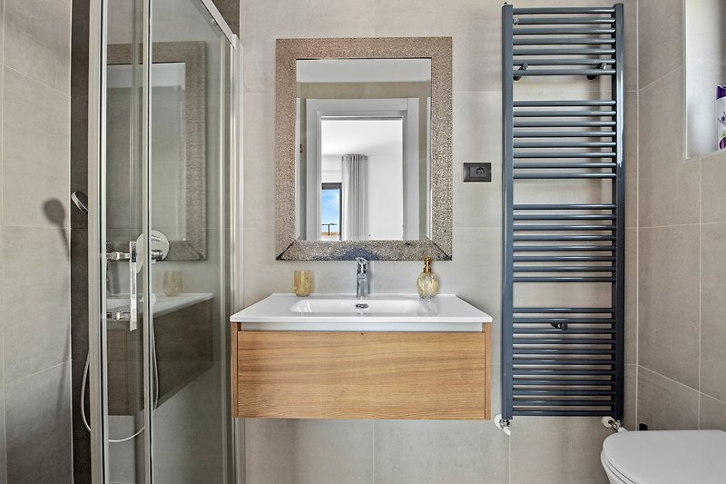 Stilvolles Badezimmer mit Spiegel, Waschbecken und moderner Armatur.