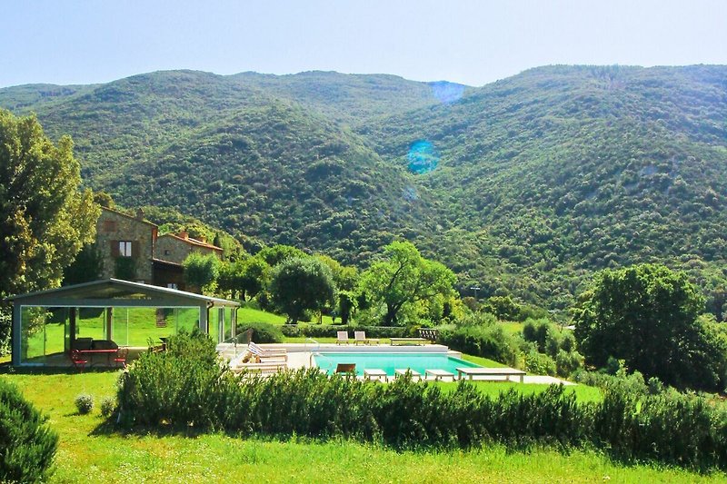 Casa immersa nella natura con montagne, alberi e prati verdi. Ideale per escursioni e relax.