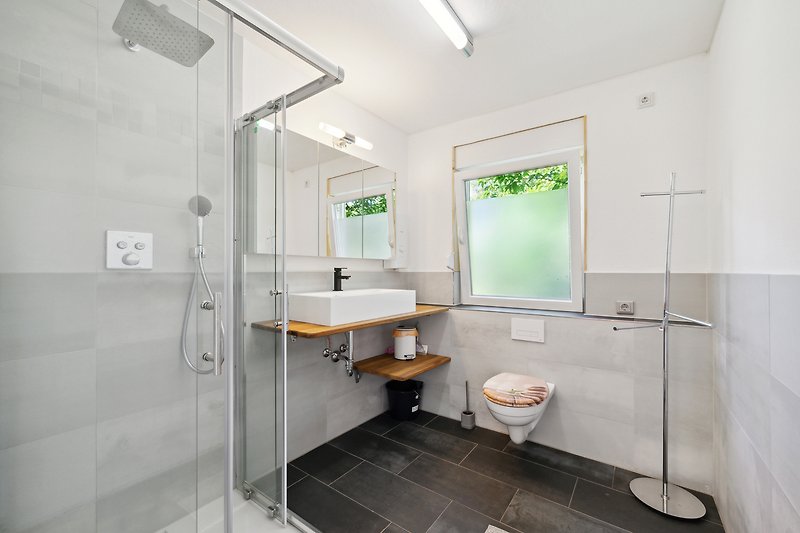 Modernes Badezimmer mit Glasdusche, Spiegel und Waschbecken.