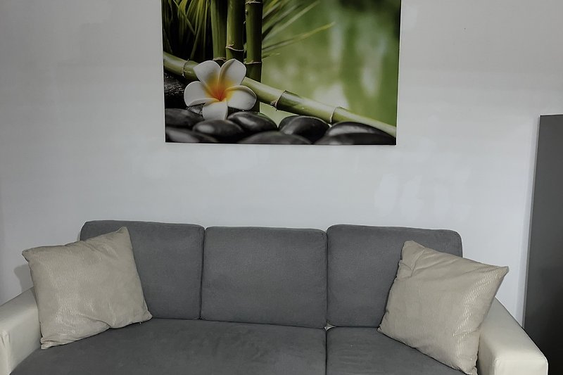 Wohnzimmer mit weißem Sofa, Holzwand, Pflanzen und Kunst.