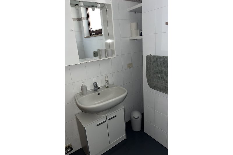Modernes Badezimmer mit Spiegel, Waschbecken und Armaturen.
