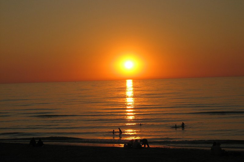 Ruhiger Sonnenuntergang am Meer mit rotem Himmel.