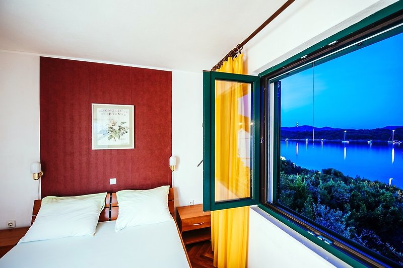 Predivan pogled na udoban apartman s drvenim namještajem i prozorima uz more.
