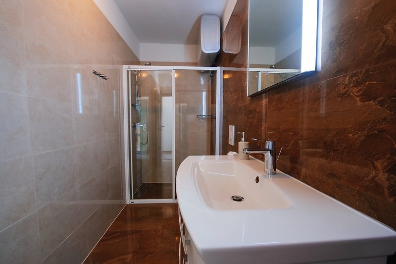 Prekrasna kupaonica s drvenim podom, ogledalom i kadom.