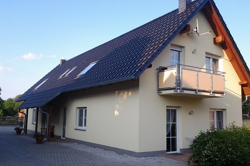 Haus mit Balkon, Fenstern und Schornstein, umgeben von Tageslicht.