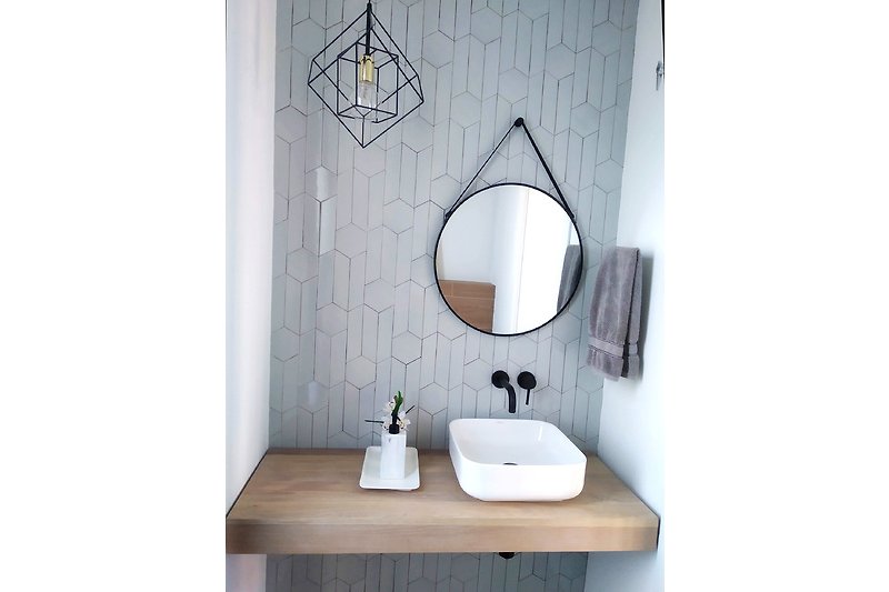 Modernes Badezimmer mit Spiegel, Waschbecken und Armatur.