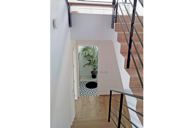 Treppe mit Handlauf, Glasgeländer und Metallakzenten.