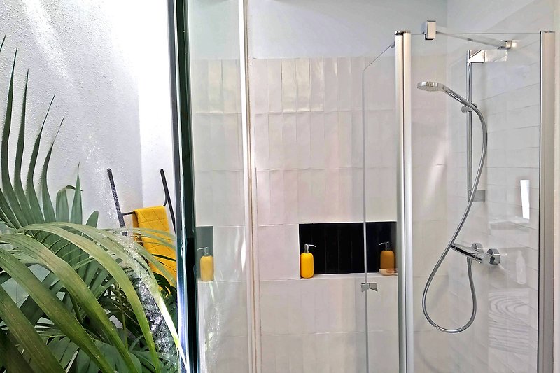 Modernes Badezimmer mit Dusche, Pflanze und Fenster.