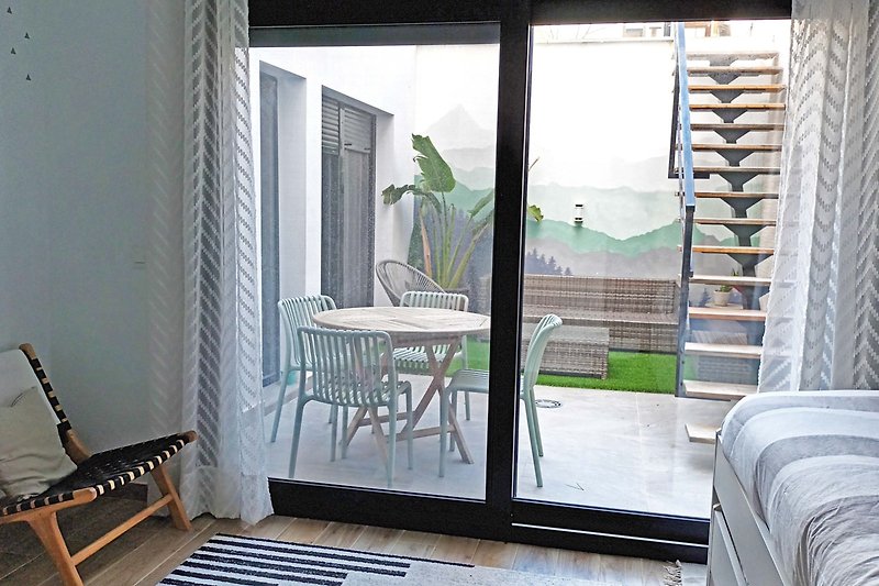Geräumiges Wohnzimmer mit Holzmöbeln, Pflanzen und Balkon.