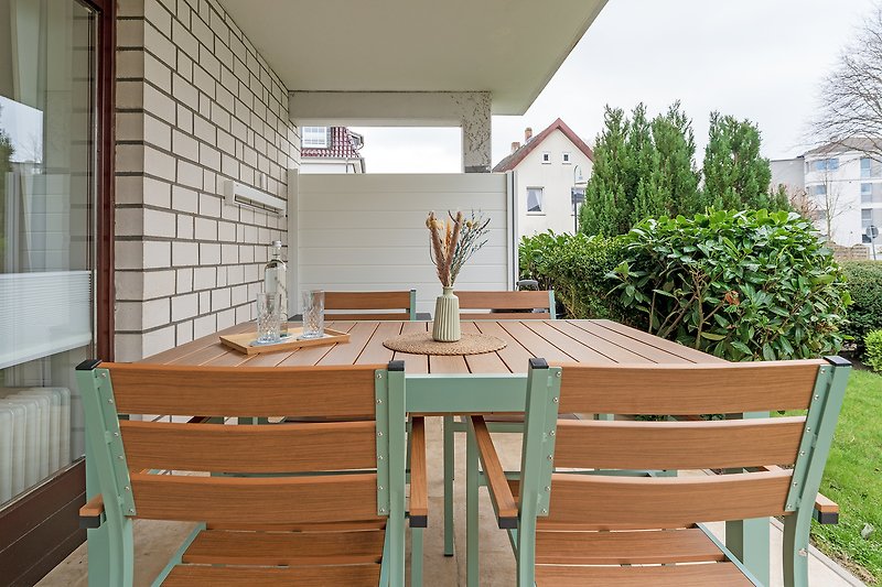 Geräumige Terrasse mit Holzmöbeln und Blick auf den Garten.