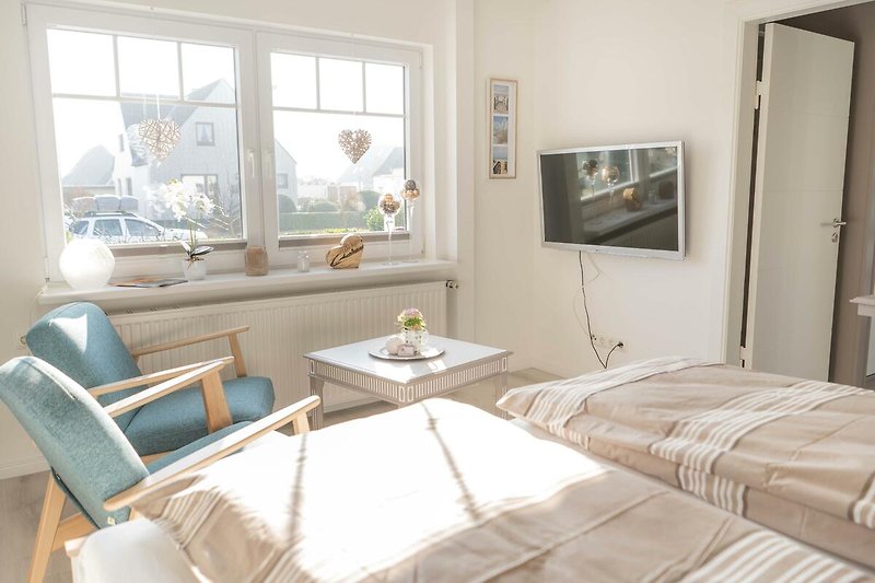 Schlafzimmer mit TV und Sesseln in der Ferienwohnung Inselblume 66 auf Fehmarn